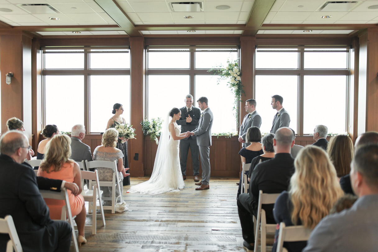 a bride and groom in a room with chairs and flowers