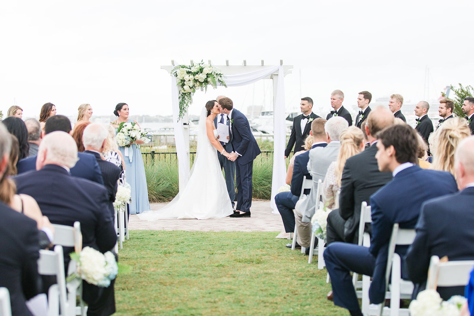a bride and groom kissing at an outdoor wedding ceremony
