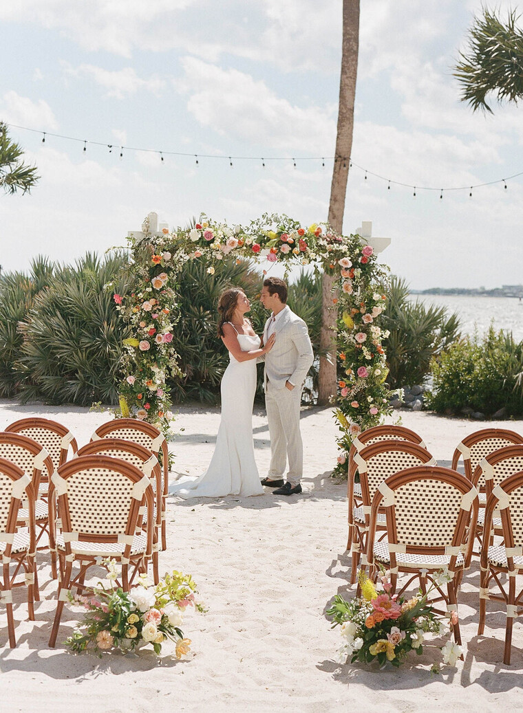 a man and woman kissing under a floral arch