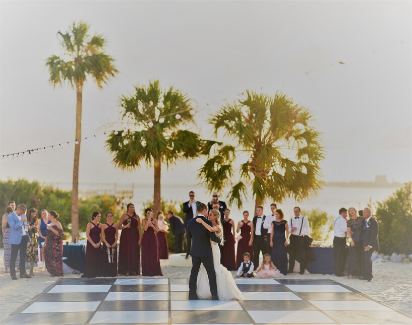 a couple dancing on a checkered floor outside with people in the background